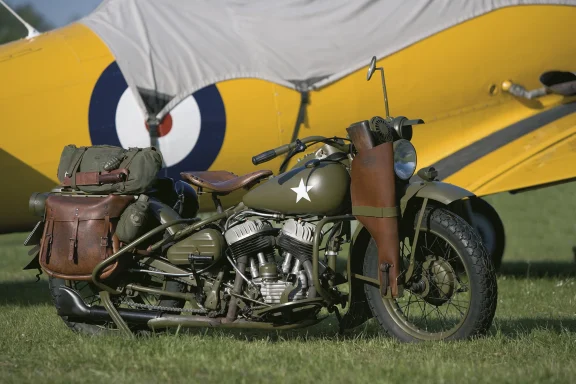 Harley-Davidson WLA der US Army vor historischem Militärflugzeug mit authentischer Militärlackierung und Ausrüstung.