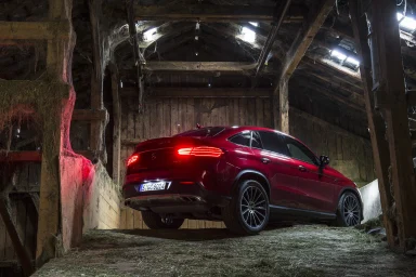 Ein rotes SUV steht in einem alten, hölzernen Scheune mit gedämpftem Licht.