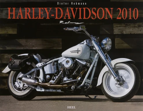 Harley-Davidson Softail Fat Boy in zweifarbiger Lackierung in Weiß und Mintgrün vor einer Holzwand.Harley Kalender 2010