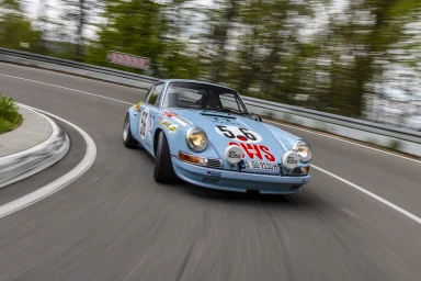 Ein blauer Sportwagen fährt mit hoher Geschwindigkeit um eine enge Kurve.