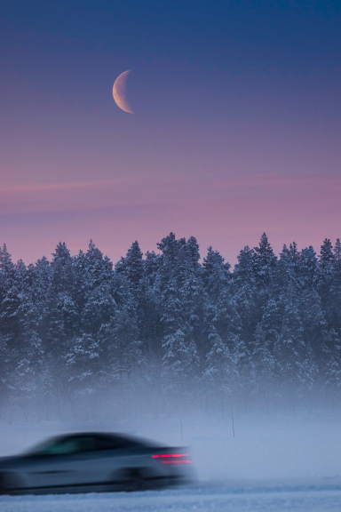 Mercedes-AMG bei der Wintererprobung in Arjeplog vor verschneitem Wald und Halbmond während der blauen Stunde.