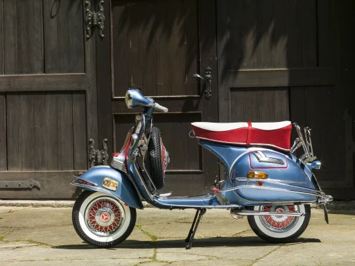 Blaue Vespa GS 150 Baujahr 1959 vor einem historischen Holztor.