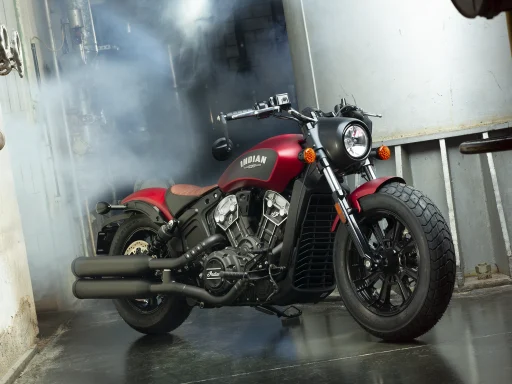 Indian Scout in matter roter Lackierung vor industrieller Kulisse mit atmosphärischer Lichtstimmung.