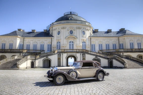 Ein klassisches Auto vor einem eleganten historischen Gebäude mit Treppen.