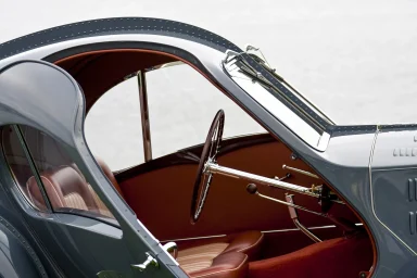 Innenraum eines historischen Sportwagens 1937 Bugatti Type 575 Atlantic mit rotem Lederinterieur und klassischem Holzlenkrad.