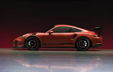 Oranger Porsche 911 GT3 RS in Seitenansicht bei einer Studioaufnahme.