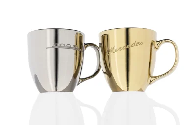 Silberne und goldfarbene Design-Tassen vor weißem Hintergrund