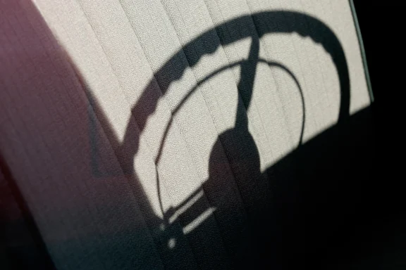 Abstrakte Darstellung des Schattens eines Lenkrads auf einer strukturierten Oberfläche mit starken Kontrasten.