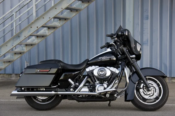 Schwarze Harley-Davidson Street Glide mit Batwing-Verkleidung und Seitenkoffern vor einer Industriehalle.