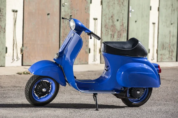 Blaue Vespa 50 N Baujahr 1977 in Seitenansicht vor historischen Garagentoren.
