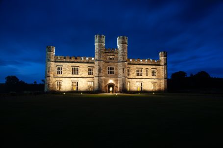 Leeds Castle in Kent bei Nacht, beleuchtete Fassade vor dunklem Himmel.
