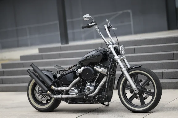 Harley-Davidson Softail Standard FXST Baujahr 2022 in Vivid Black mit Apehanger-Lenker und Weißwandreifen vor moderner Architektur.i