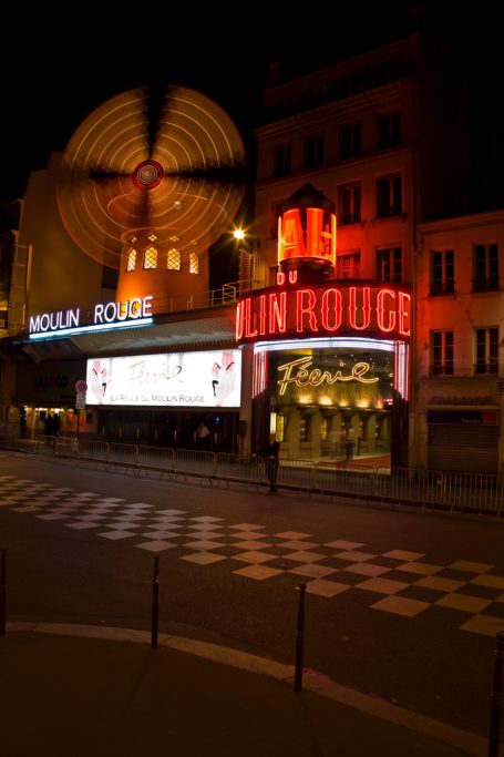 Moulin Rouge in Paris bei Nacht mit beleuchtetem Eingang und roter Reklame.