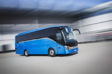Blauer Setra S 511 HD Reisebus in einer dynamischen Rig-Aufnahme vor moderner Architektur.