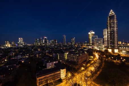 Frankfurter Skyline bei Nacht mit beleuchteten Hochhäusern.