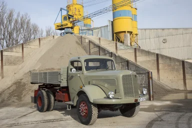Historischer Mercedes-Benz Lastwagen vor Sandlager und Siloanlage in einem Baustoffwerk.