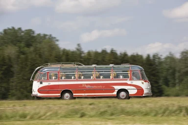 Setra S 10 Oldtimer-Reisebus in dynamischer Fahrt durch eine ländliche Landschaft.