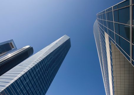 Moderne Hochhäuser aus ungewöhnlicher Perspektive vor blauem Himmel.