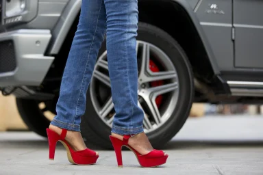 Rote High Heels vor einer Mercedes-AMG G-Klasse, farblich abgestimmt auf die roten Bremssättel.
