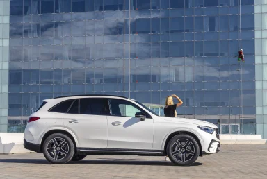 Mercedes-Benz GLC vor einer modernen Glasfassade mit Fensterputzer in großer Höhe.