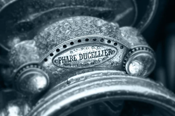 Detail eines historischen Automobils mit Phare-Ducellier-Scheinwerfer und Regentropfen.
