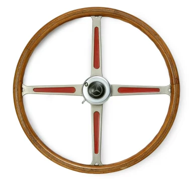 Historisches Mercedes-Benz Lenkrad aus Holz und Metall mit roten Zierelementen, freigestellt vor hellem Hintergrund.
