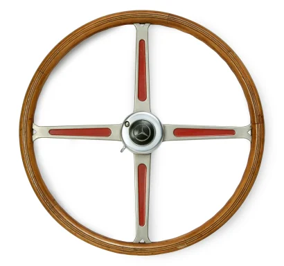 Historisches Mercedes-Benz Lenkrad aus Holz und Metall mit roten Zierelementen, freigestellt vor hellem Hintergrund.