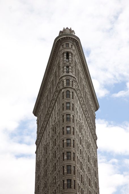 Flatiron Building in New York aus ungewöhnlicher Perspektive vor blauem Himmel.