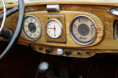 Instrumententafel eines historischen Automobils mit Holzarmaturen und analoger Uhr.