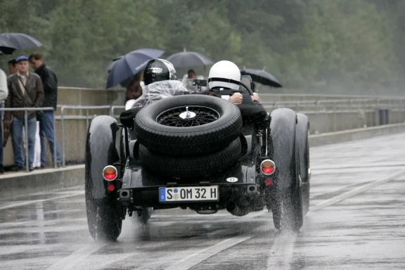 Mercedes-Benz SSK auf nasser Rennstrecke im Regen mit aufspritzendem Wasser und Fahrern im Cockpit – Automobil Moments von Dieter Rebmann.