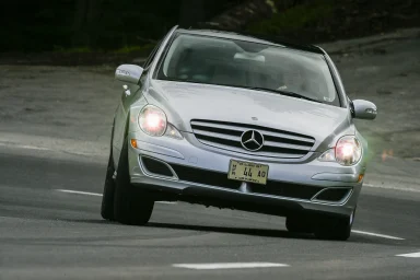 Silberne Mercedes-Benz R-Klasse in dynamischer Kurvenfahrt auf einer Landstraße.
