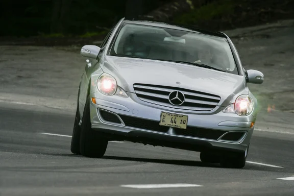 Silberne Mercedes-Benz R-Klasse in dynamischer Kurvenfahrt auf einer Landstraße.