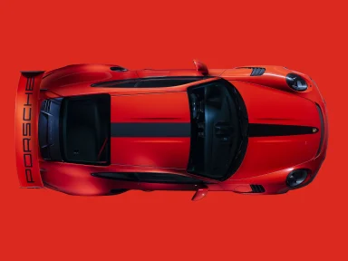 Roter Porsche 911 GT3 RS in Draufsicht auf rotem Hintergrund mit schwarzem Mittelstreifen und großem Heckflügel.